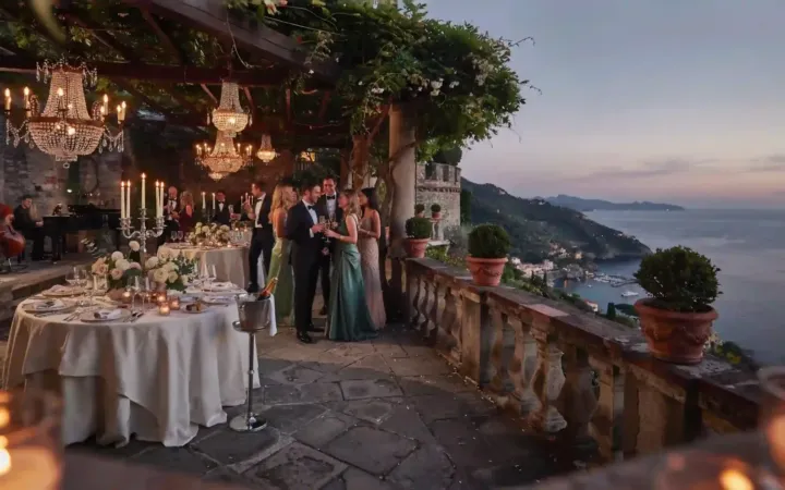 Recepción de gala y banquete en la terraza de un castillo en Portofino, Italia, iluminado durante el atardecer.