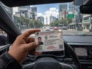 Licencia de conducir permanente de la Ciudad de México sostenida al volante de un automóvil.